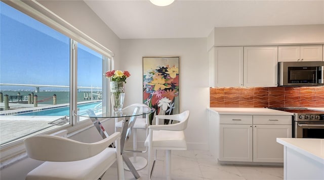 kitchen with tasteful backsplash, white cabinets, and appliances with stainless steel finishes