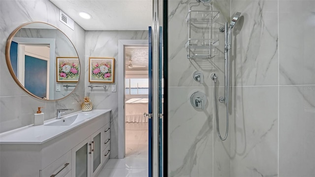 bathroom featuring vanity, tiled shower, and tile walls