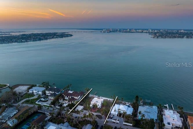 aerial view at dusk featuring a water view