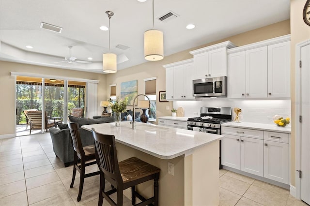 kitchen featuring white cabinetry, decorative light fixtures, a kitchen island with sink, and stainless steel appliances