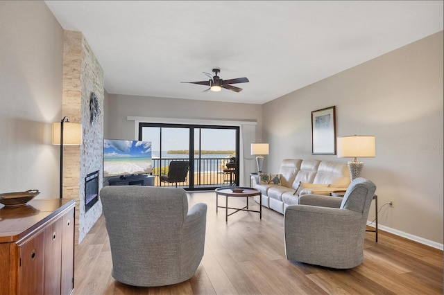 living room with ceiling fan, a fireplace, and light hardwood / wood-style flooring