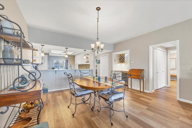 dining area with ceiling fan with notable chandelier and light hardwood / wood-style flooring