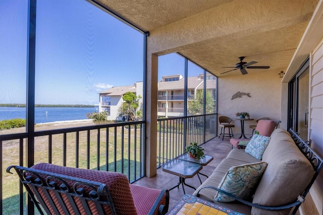 sunroom / solarium with a water view and ceiling fan