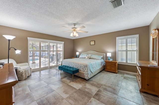 tiled bedroom with ceiling fan, a textured ceiling, multiple windows, and access to outside