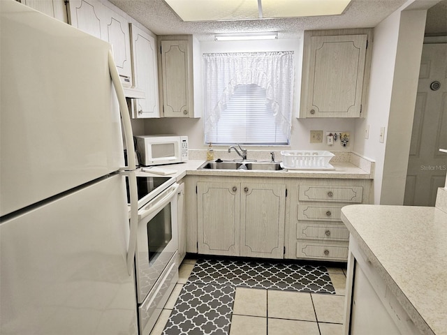 kitchen featuring white appliances, sink, a textured ceiling, and light tile patterned floors