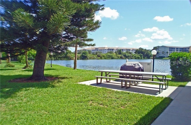 surrounding community with a water view and a yard