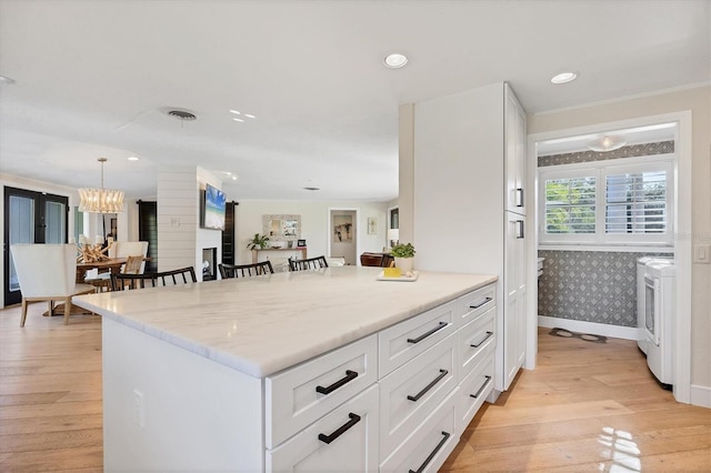 kitchen featuring pendant lighting, white cabinets, a kitchen breakfast bar, light hardwood / wood-style floors, and light stone countertops