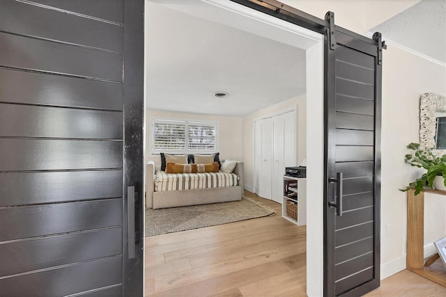 bedroom with light hardwood / wood-style floors and a barn door