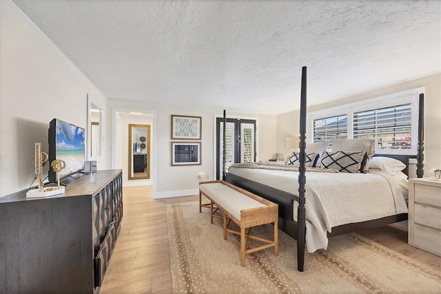 bedroom featuring crown molding, light hardwood / wood-style floors, and a textured ceiling