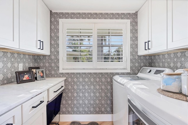 clothes washing area with washing machine and dryer and cabinets