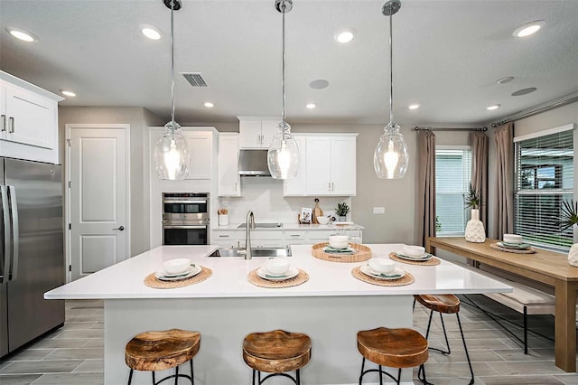 kitchen with stainless steel appliances, white cabinetry, and decorative light fixtures