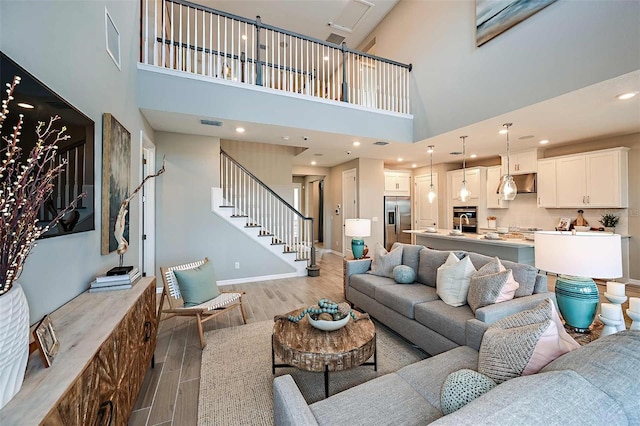 living room with a towering ceiling and light hardwood / wood-style flooring