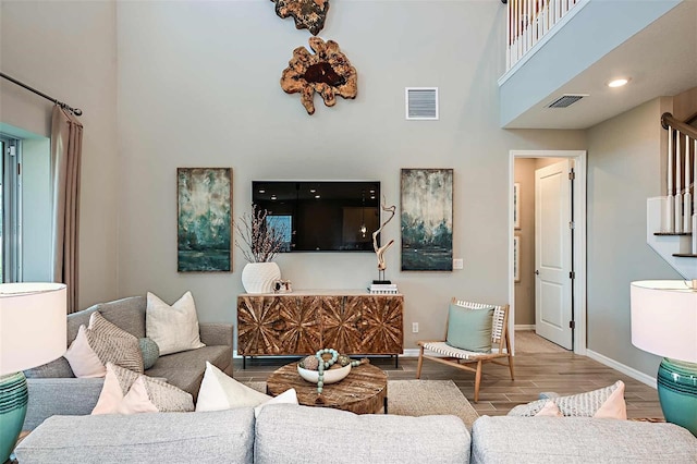 living room featuring a towering ceiling and hardwood / wood-style floors