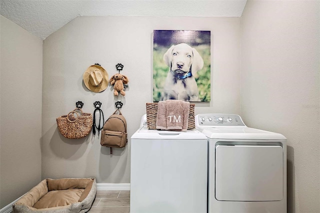 clothes washing area with washing machine and dryer and a textured ceiling