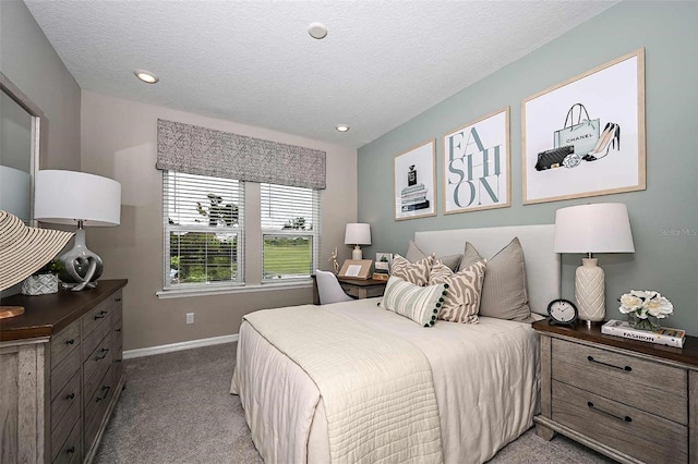 bedroom with light colored carpet and a textured ceiling