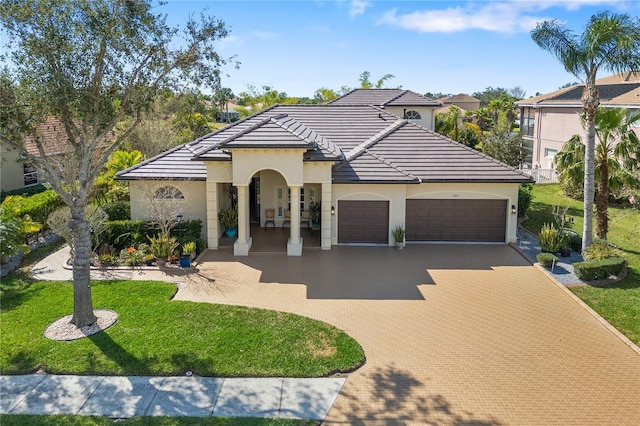 view of front facade featuring a garage, a tiled roof, decorative driveway, and a front yard