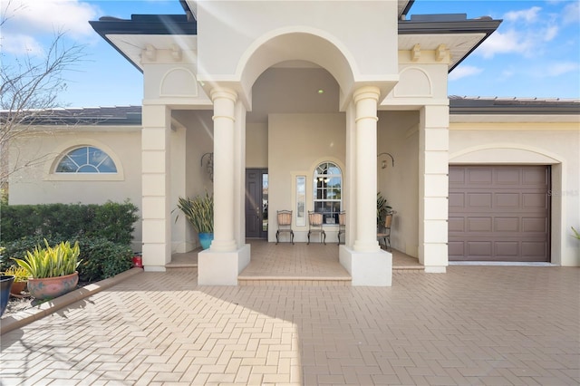 property entrance featuring a porch, decorative driveway, and stucco siding