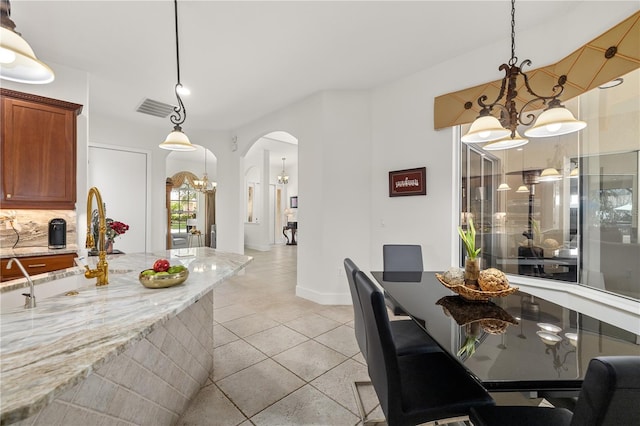 dining space with arched walkways, light tile patterned floors, visible vents, a chandelier, and baseboards