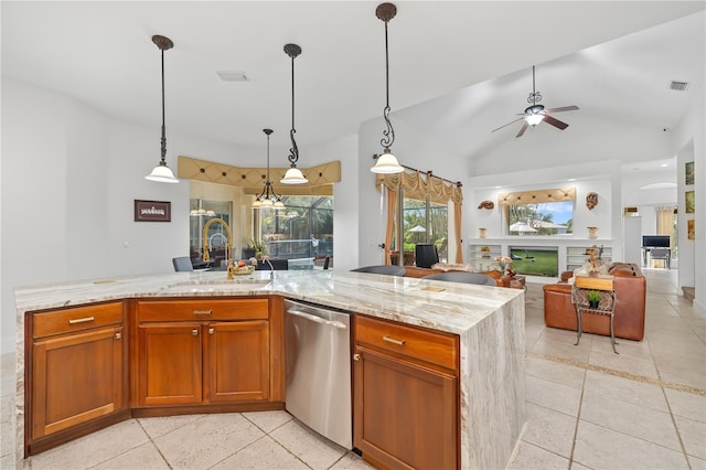 kitchen with hanging light fixtures, stainless steel dishwasher, open floor plan, a sink, and light stone countertops