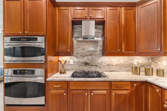 kitchen with stainless steel appliances, tasteful backsplash, wall chimney range hood, and light stone countertops