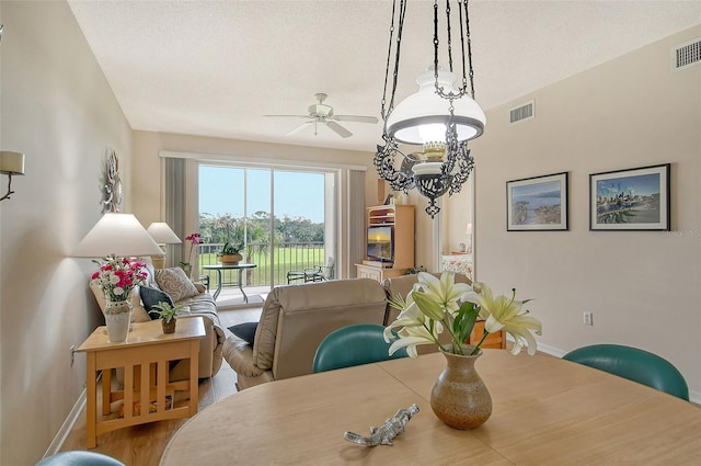 dining area featuring hardwood / wood-style floors, a textured ceiling, and ceiling fan