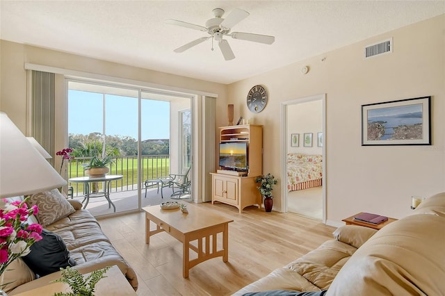 living room featuring a textured ceiling, light hardwood / wood-style flooring, and ceiling fan