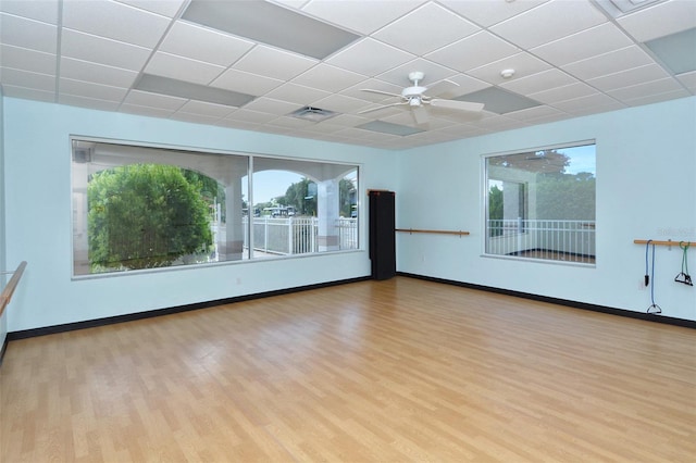 unfurnished room with a wealth of natural light, a drop ceiling, ceiling fan, and light hardwood / wood-style flooring