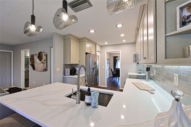 kitchen with stainless steel refrigerator with ice dispenser, decorative light fixtures, kitchen peninsula, and tasteful backsplash