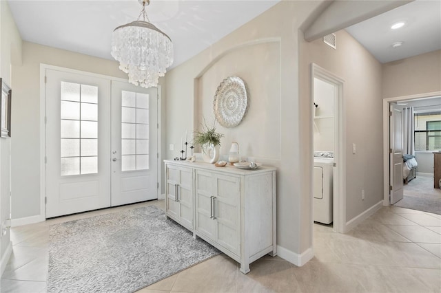 tiled entrance foyer featuring french doors, washer / clothes dryer, and a notable chandelier