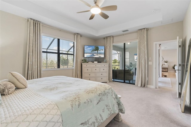 bedroom with multiple windows, a raised ceiling, access to outside, and light colored carpet