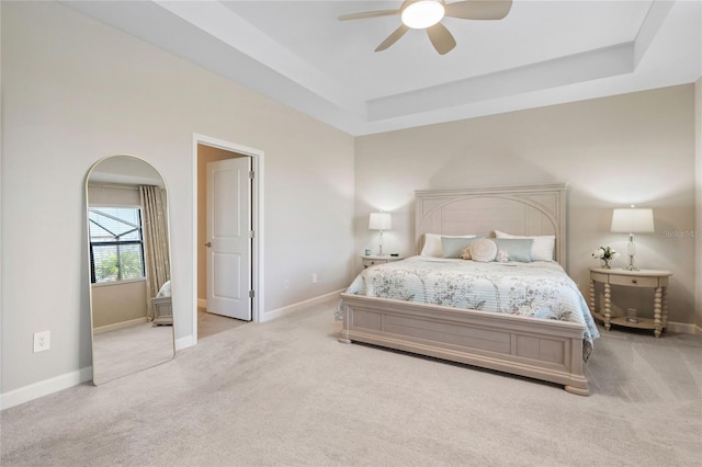 carpeted bedroom with ceiling fan and a tray ceiling