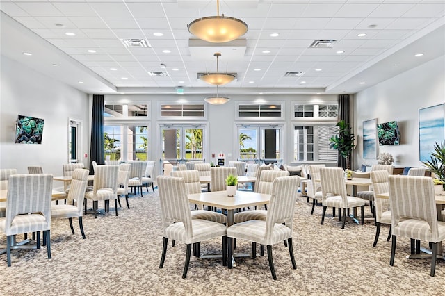 dining space with light colored carpet and a towering ceiling