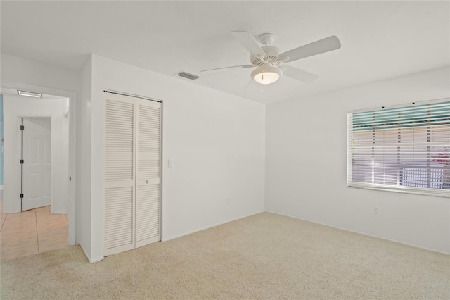 unfurnished bedroom featuring light carpet, ceiling fan, and a closet