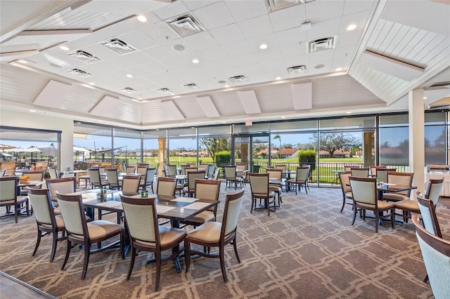 carpeted dining space with a healthy amount of sunlight and a high ceiling