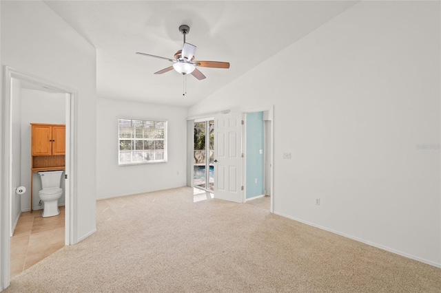 unfurnished bedroom featuring light tile patterned flooring, ensuite bathroom, lofted ceiling, and light colored carpet