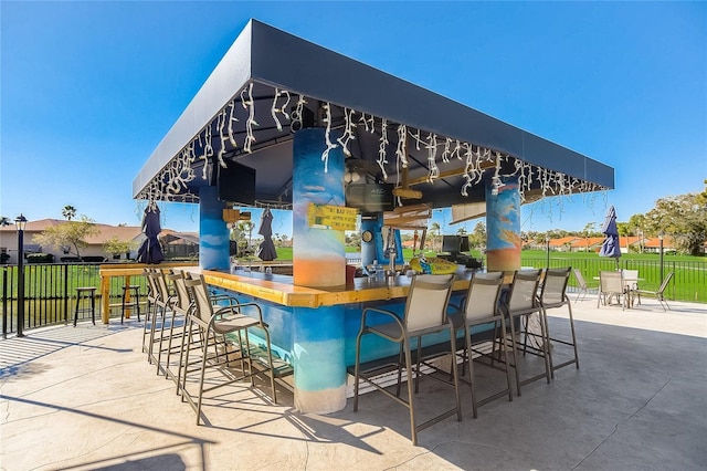 view of patio featuring a bar and fence
