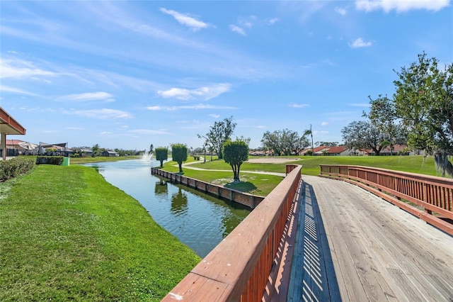 view of dock with a water view and a lawn