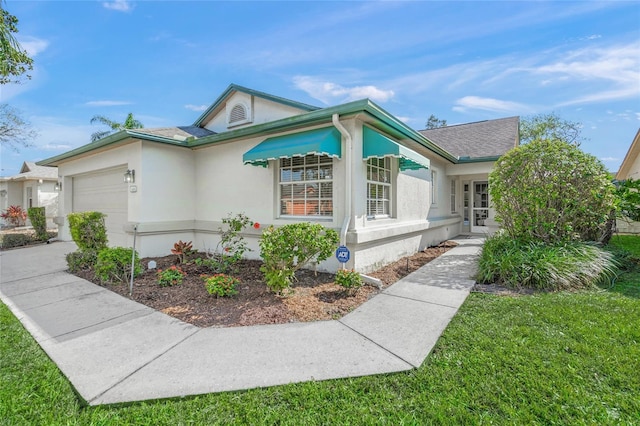 view of front of property with stucco siding, concrete driveway, a front lawn, and an attached garage
