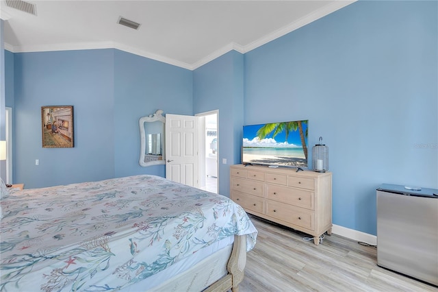 bedroom with ornamental molding, stainless steel fridge, and light hardwood / wood-style floors