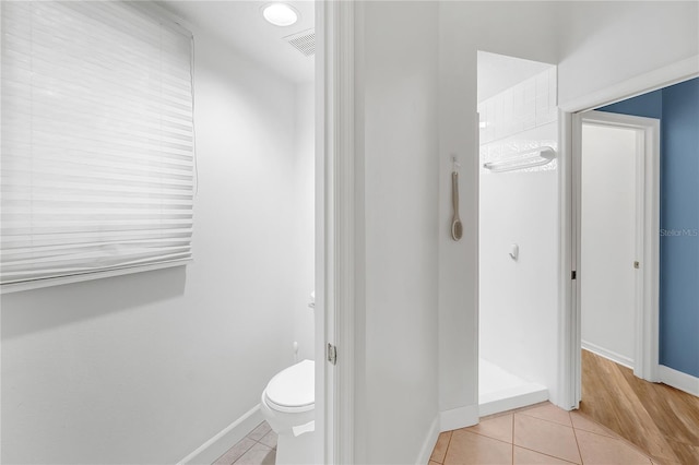 bathroom with a shower, tile patterned floors, and toilet