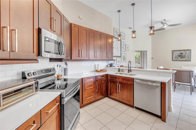 kitchen featuring pendant lighting, sink, appliances with stainless steel finishes, backsplash, and kitchen peninsula