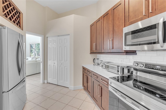 kitchen with tasteful backsplash, light tile patterned flooring, and appliances with stainless steel finishes