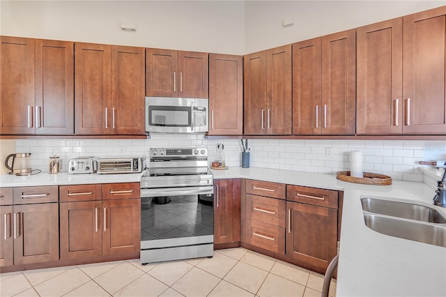 kitchen with light tile patterned floors, appliances with stainless steel finishes, sink, and backsplash