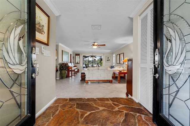 foyer with crown molding, ceiling fan, and a textured ceiling