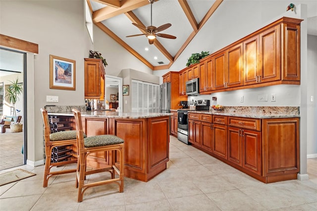 kitchen featuring light stone counters, light tile patterned floors, appliances with stainless steel finishes, beamed ceiling, and ceiling fan