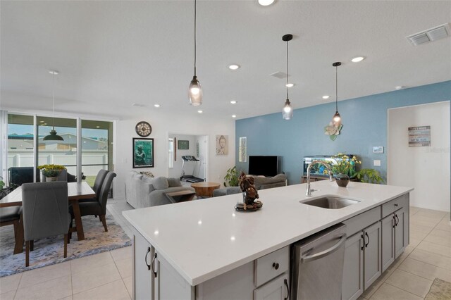 kitchen featuring dishwasher, sink, pendant lighting, and a kitchen island with sink