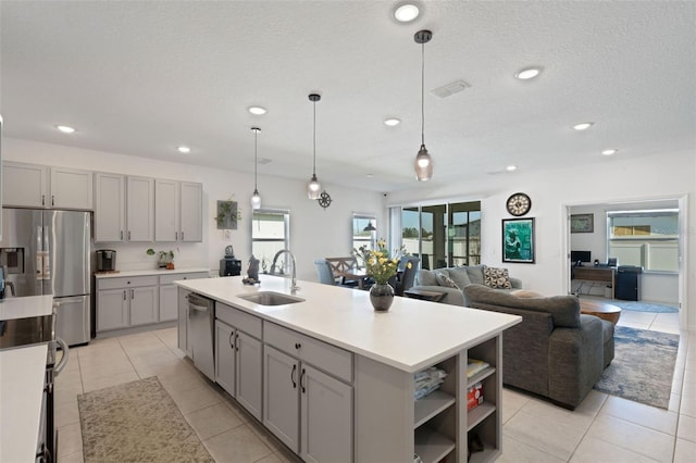 kitchen featuring a kitchen island with sink, sink, gray cabinets, and appliances with stainless steel finishes