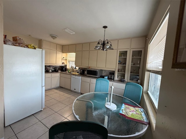 kitchen featuring pendant lighting, white cabinets, light tile patterned floors, a notable chandelier, and white appliances