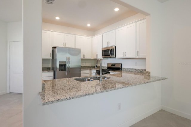 kitchen featuring white cabinetry, appliances with stainless steel finishes, kitchen peninsula, and light stone counters