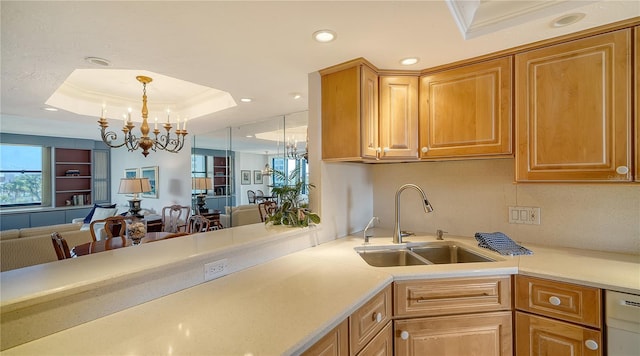 kitchen featuring sink, stainless steel dishwasher, a tray ceiling, a notable chandelier, and pendant lighting